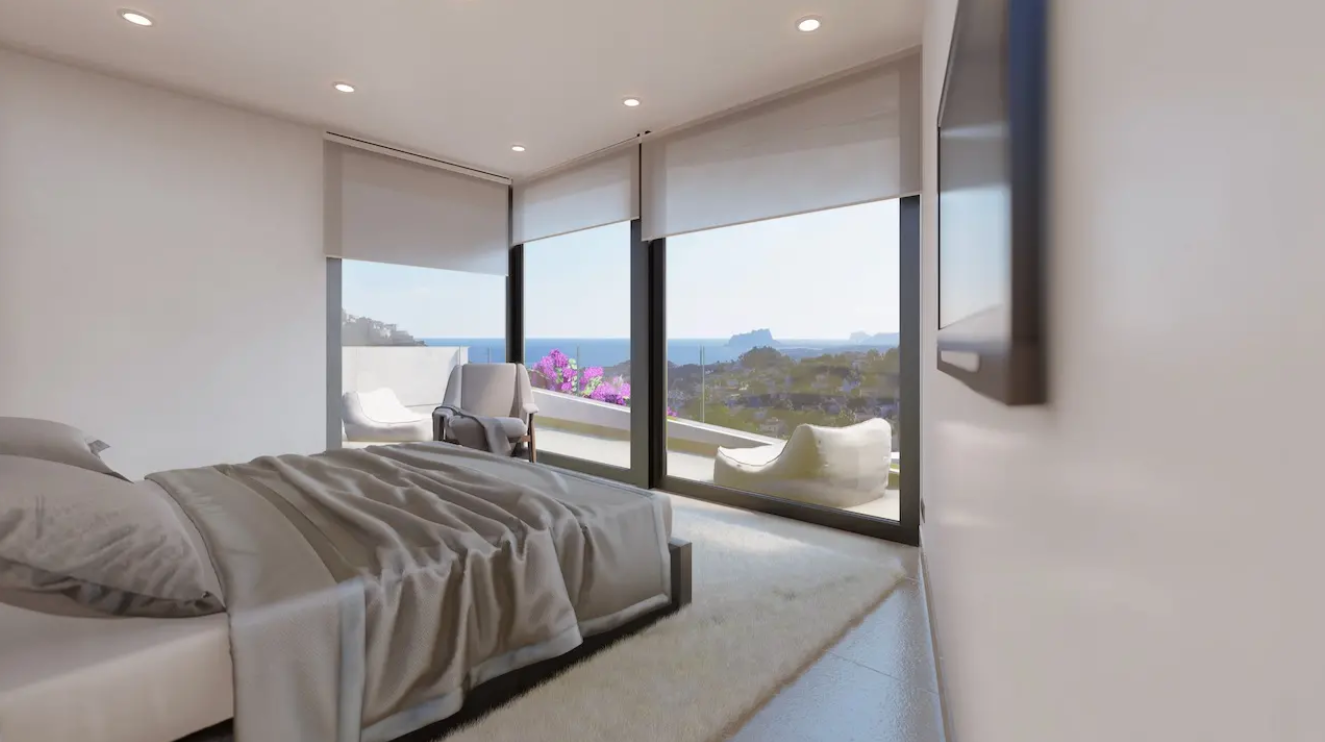 Modern bedroom featuring floor-to-ceiling windows with panoramic views of the Mediterranean and Peñón de Ifach, integrated with a private terrace.