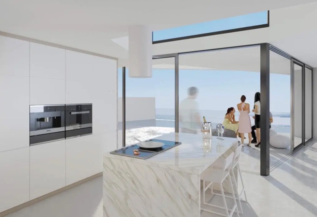 Modern kitchen featuring a marble-clad island with integrated cooktop, minimalist white cabinetry, and floor-to-ceiling glass doors opening to a terrace with sea views.