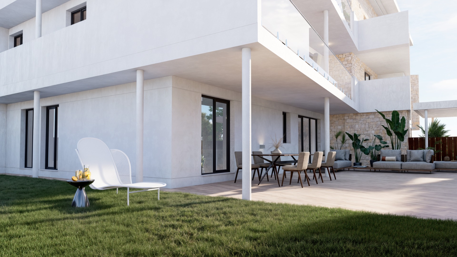 Ground floor terrace featuring wood-effect flooring, a private lawn, and modern outdoor furniture. The white facade is accented by natural stone walls and glass balcony railings.