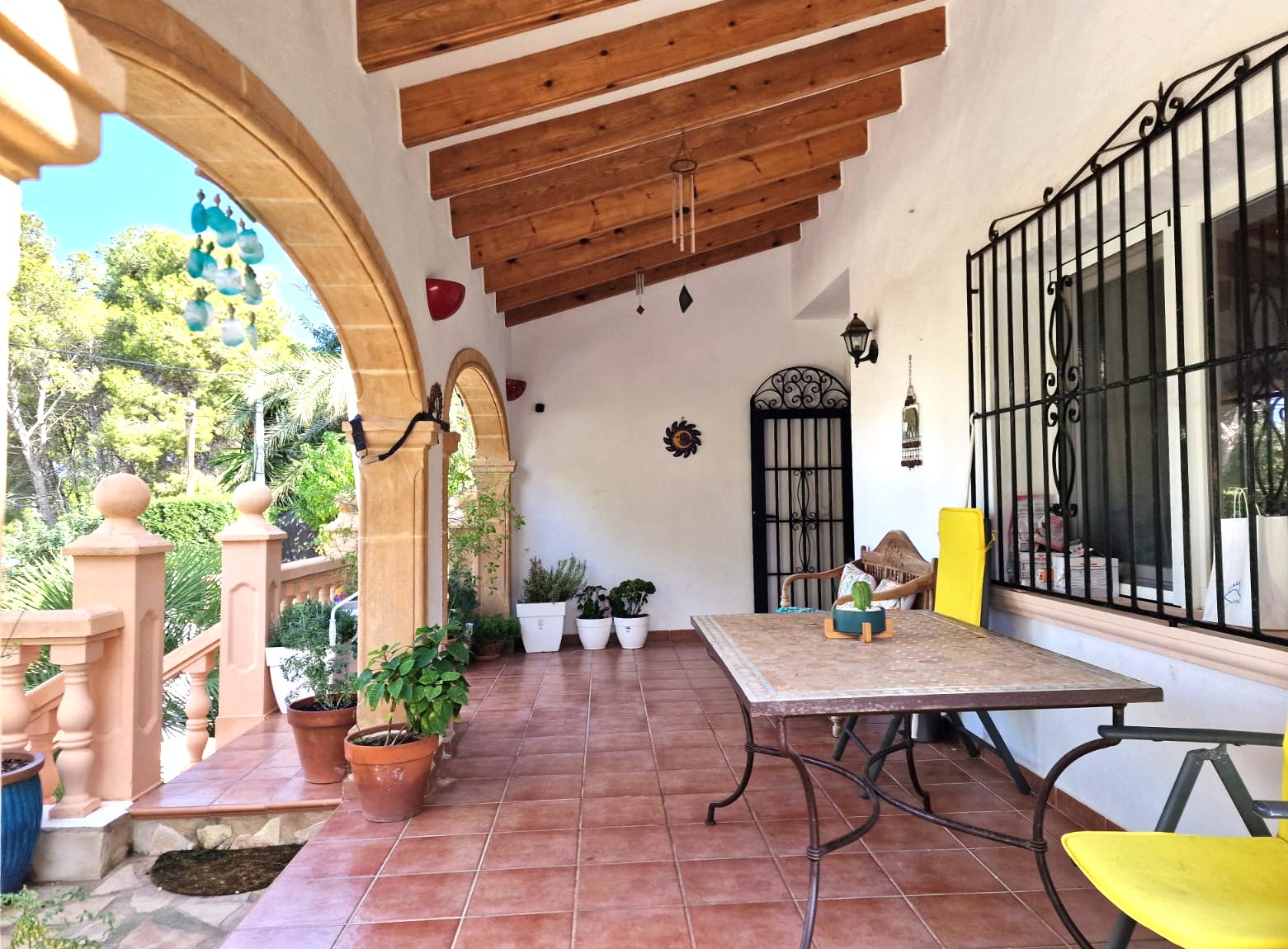 Covered terrace featuring traditional Tosca stone arches, exposed wooden beams, and terracotta flooring. Includes a dining area with views of the surrounding greenery.