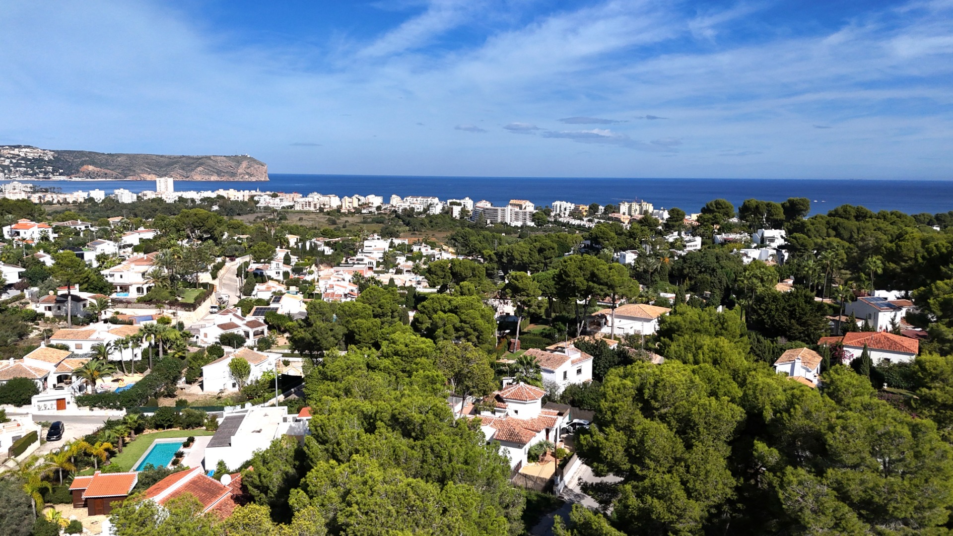 Elevated panoramic view of the Toscal residential area in Jávea, showcasing Mediterranean villas nestled among pines with Cabo de San Antonio in the distance.