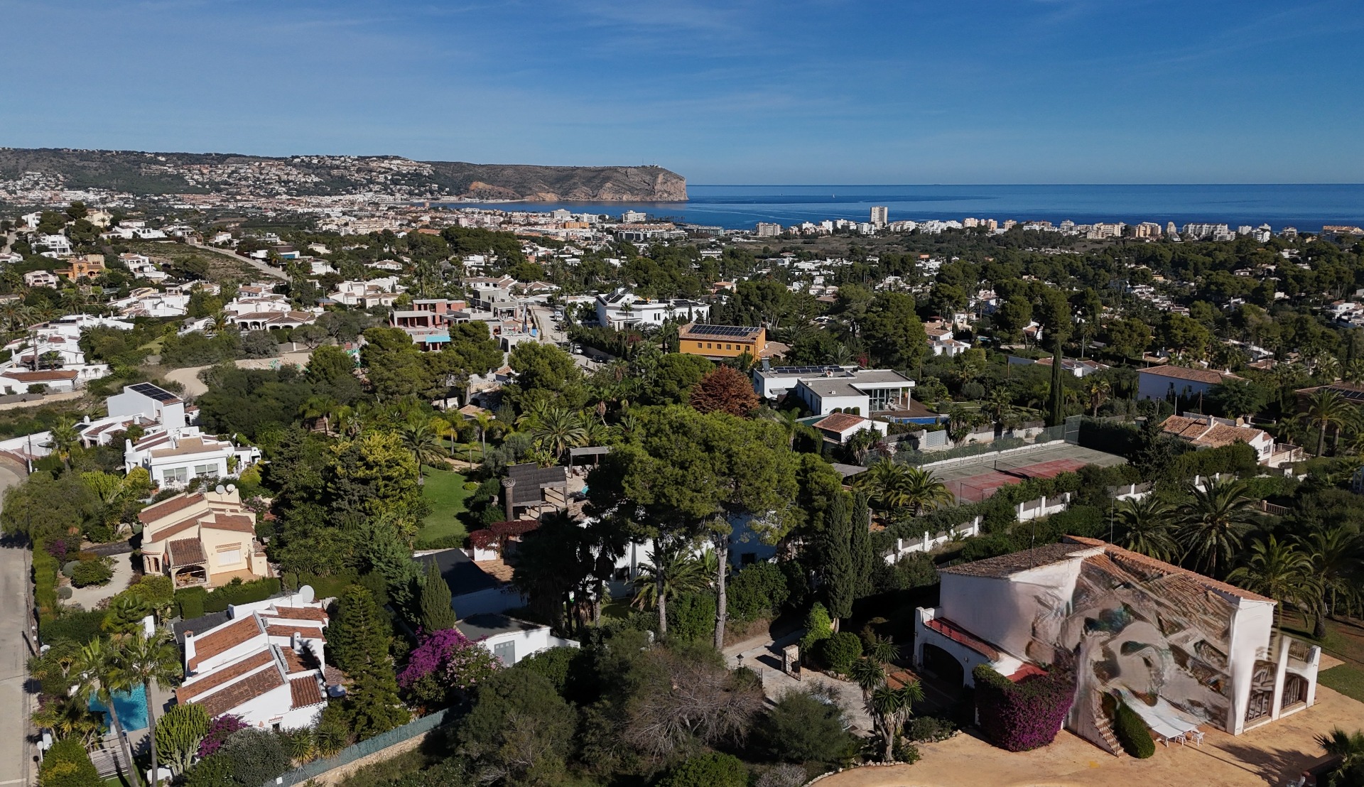 Panoramic aerial view of the Pinosol residential area in Jávea, showing the proximity to the Mediterranean Sea and the iconic Cabo de San Antonio headland.