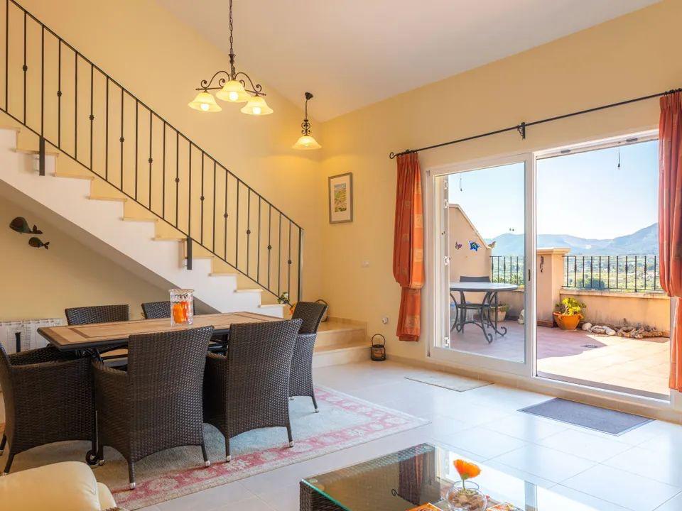Bright dining area featuring a wrought-iron staircase and sliding doors that open onto a terrace with panoramic mountain views.
