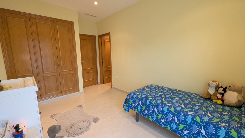 Child's bedroom with a four-door built-in wooden wardrobe, ceramic tile flooring, and integrated air conditioning vents in the ceiling.