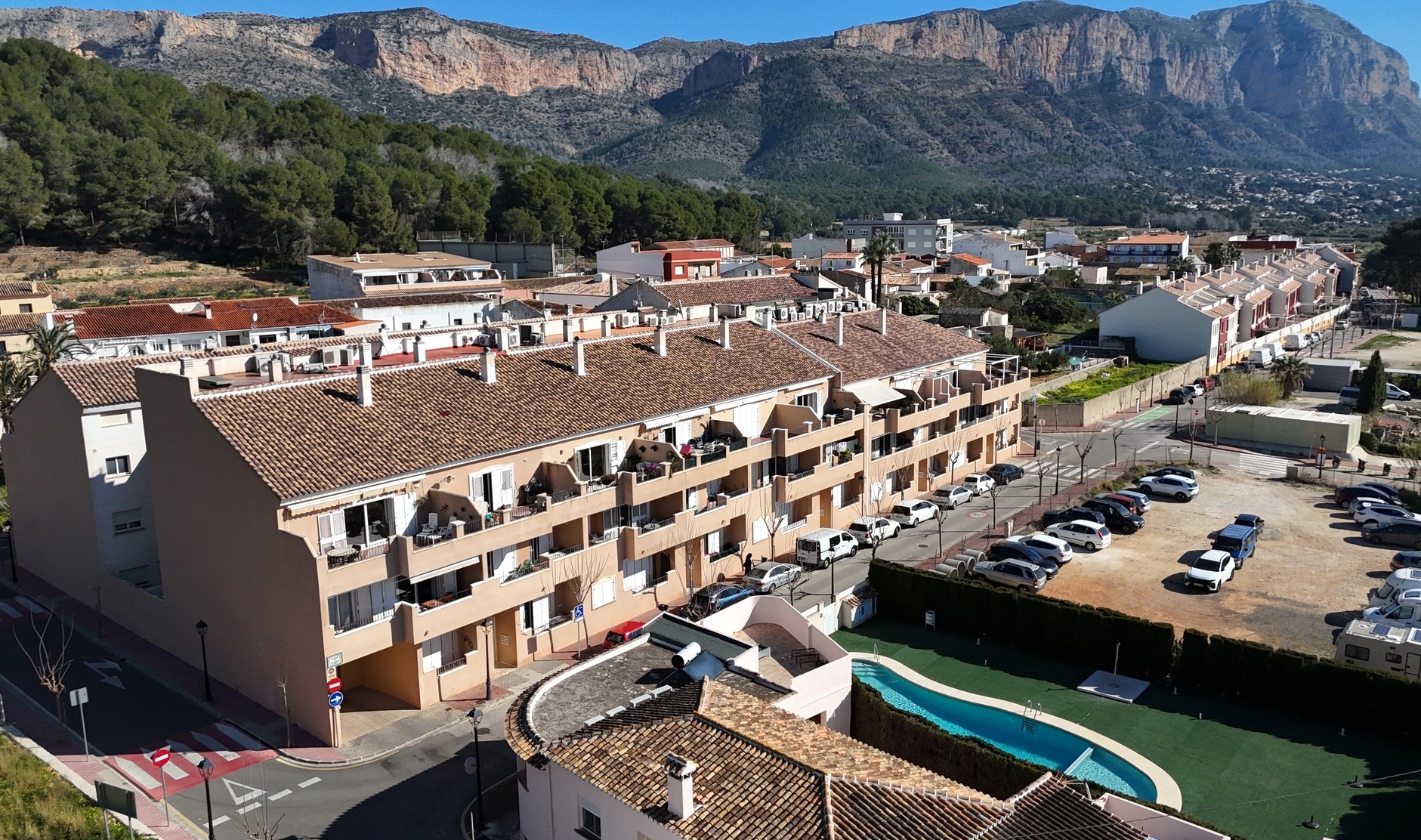 Elevated view of the residential complex in Jesús Pobre, showing the communal pool, terracotta tiled roofs, and the Montgó mountain backdrop.