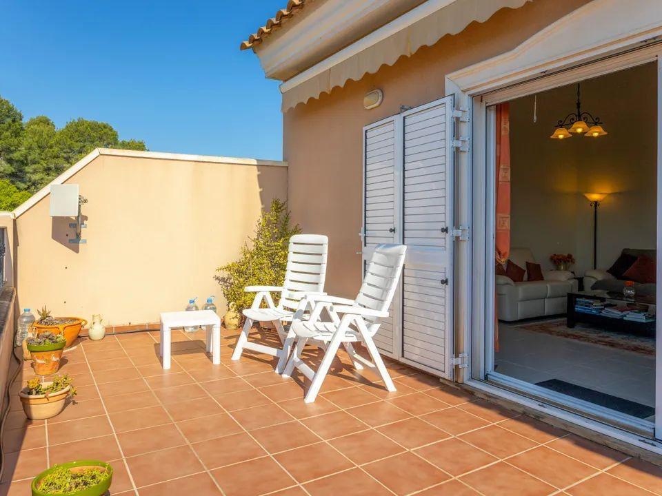 Outdoor terrace featuring terracotta tiling, white folding chairs, and direct access to the living area through sliding doors with white shutters.