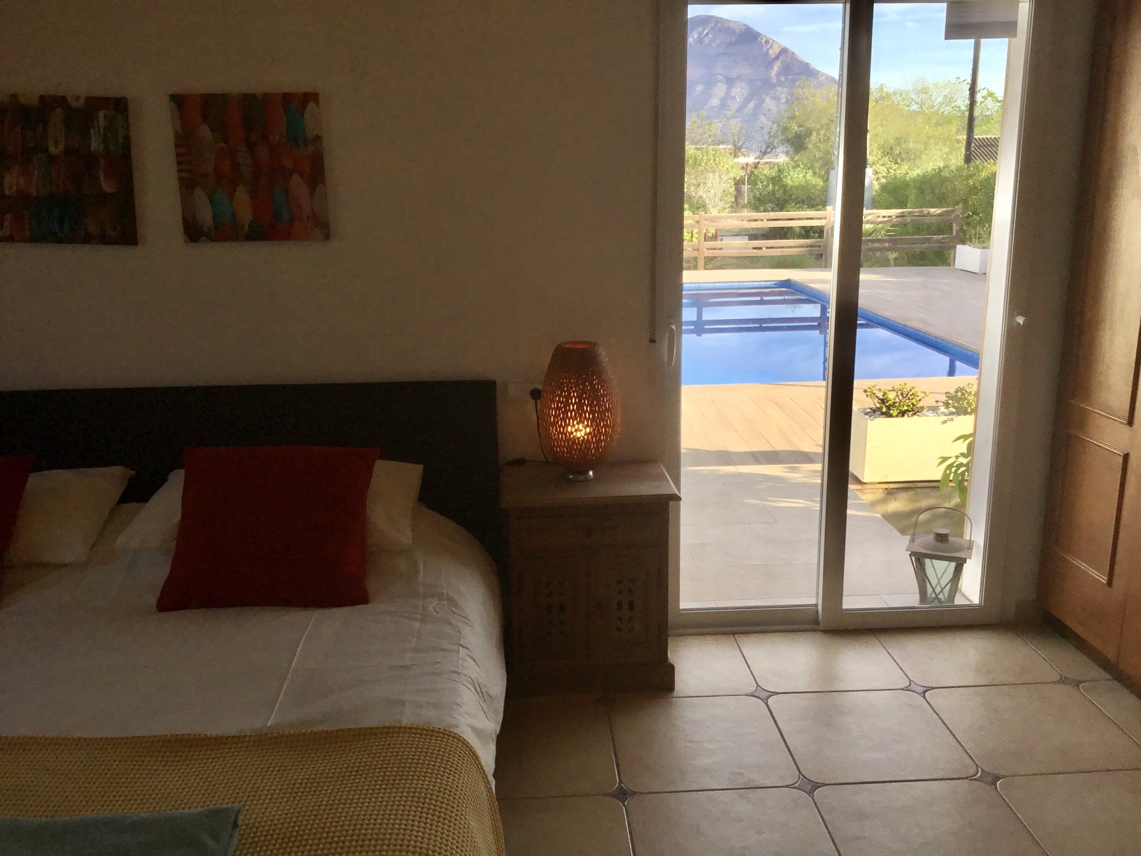Bedroom with direct access to the pool terrace through sliding glass doors, featuring views of the Montgó mountain and tiled flooring.