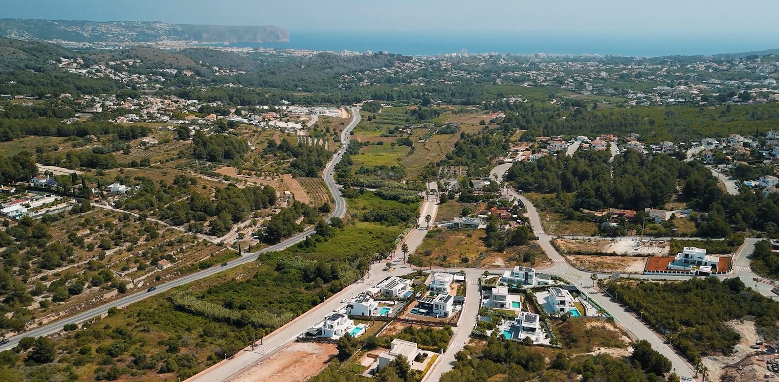 Aerial view of the Villas del Vent residential area in Jávea, showcasing modern villas and plots with panoramic views of the Mediterranean Sea and coastline.