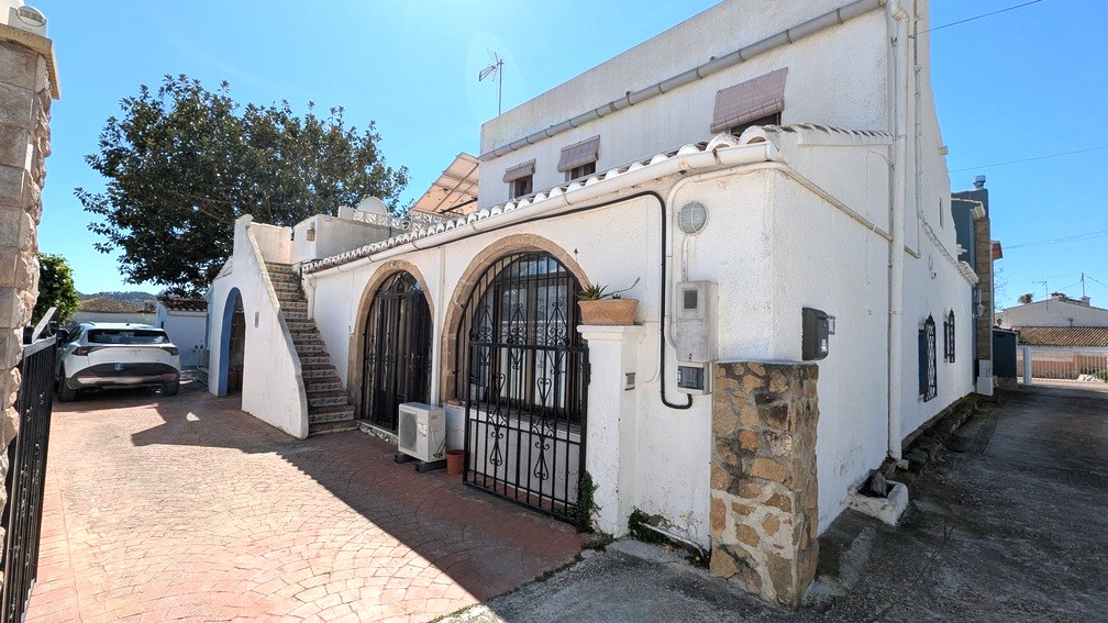 Exterior view featuring traditional Tosca stone arches with wrought iron grills, a tiled outdoor staircase, and solar panels installed on the upper terrace.