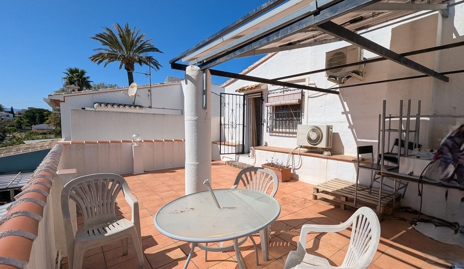 First-floor south-facing terrace with terracotta tiling, a metal pergola frame, and external air conditioning units overlooking the local landscape and palm trees.