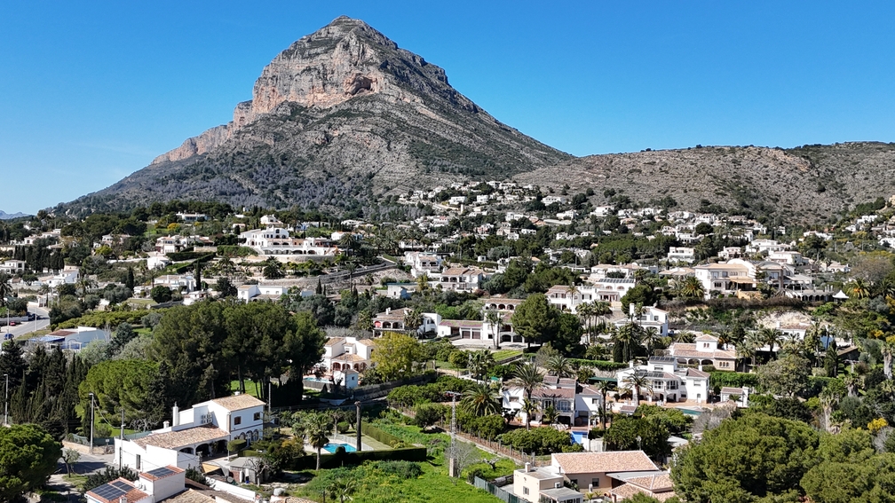 Panoramic view of the Montgó mountain overlooking the residential landscape of Javea, featuring traditional white villas and lush Mediterranean greenery.