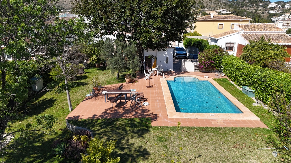 Private swimming pool set within a terracotta-tiled sun terrace and lawn. Mature trees and hedges provide privacy for the outdoor dining area and garden.