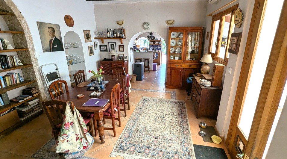 Spacious dining room featuring traditional terracotta tiling, a large wooden table, and authentic Tosca stone arches with built-in shelving and kitchen access.