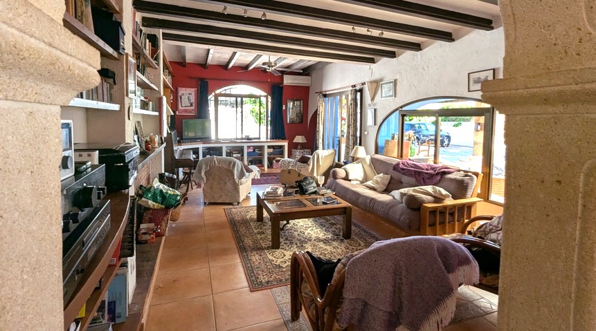 Spacious living room featuring traditional dark wood ceiling beams, Tosca stone arches, terracotta flooring, and large windows for natural light.
