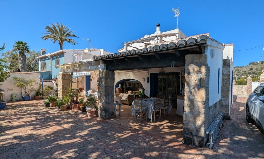 Traditional south-facing naya with Tosca stone pillars and wooden beams, featuring an outdoor dining area and lounge overlooking the paved patio garden.