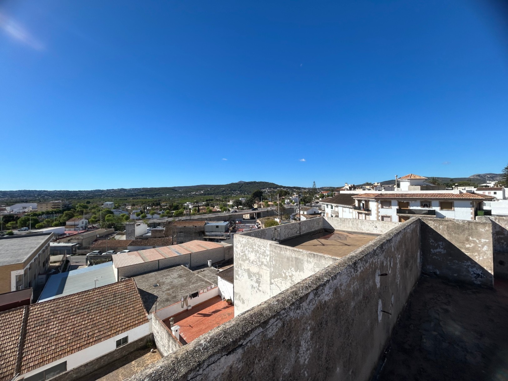 Elevated perspective from the communal roof terrace, featuring panoramic views of the Jávea townscape and distant mountain ranges.