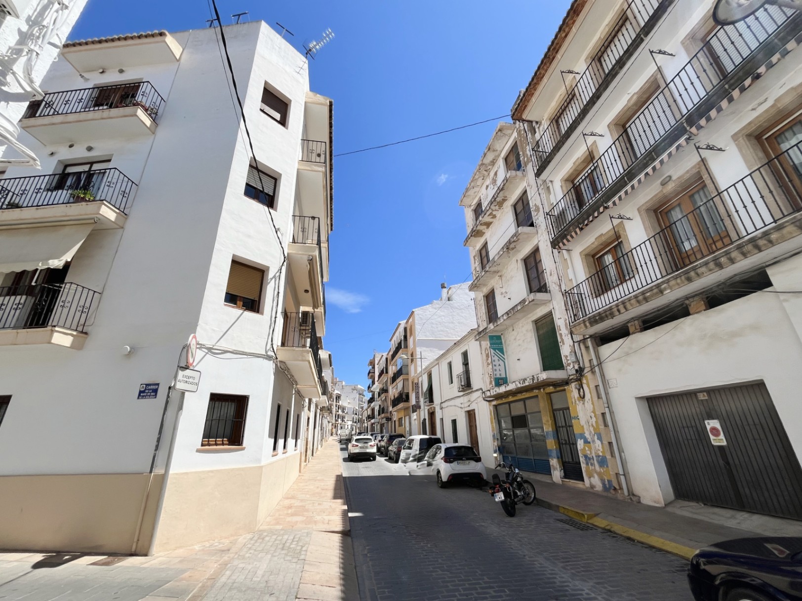 Exterior view of the four-story building in Jávea's town center, featuring a white facade with wrought-iron balconies and a spacious ground-floor commercial unit.