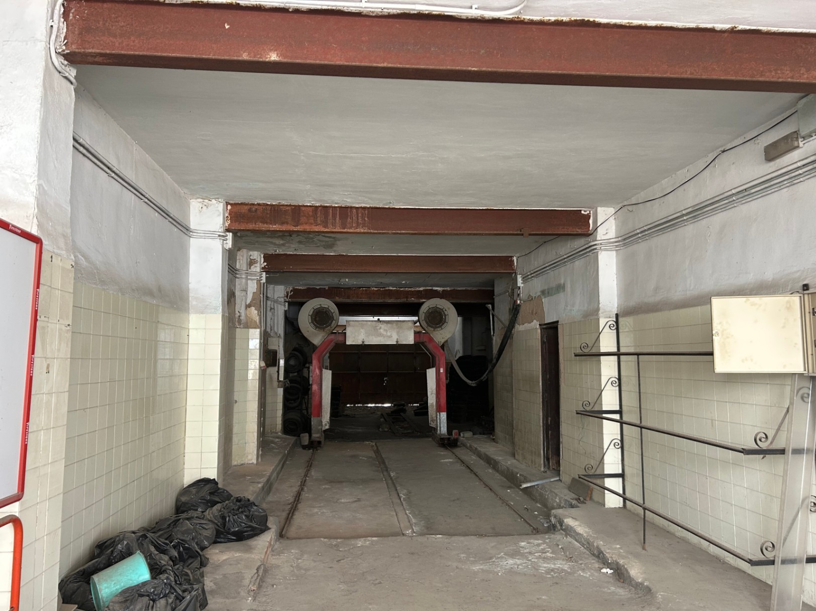 Ground floor commercial space of 175 sqm featuring high ceilings, exposed steel beams, and industrial tracks, offering vast potential for renovation or conversion.