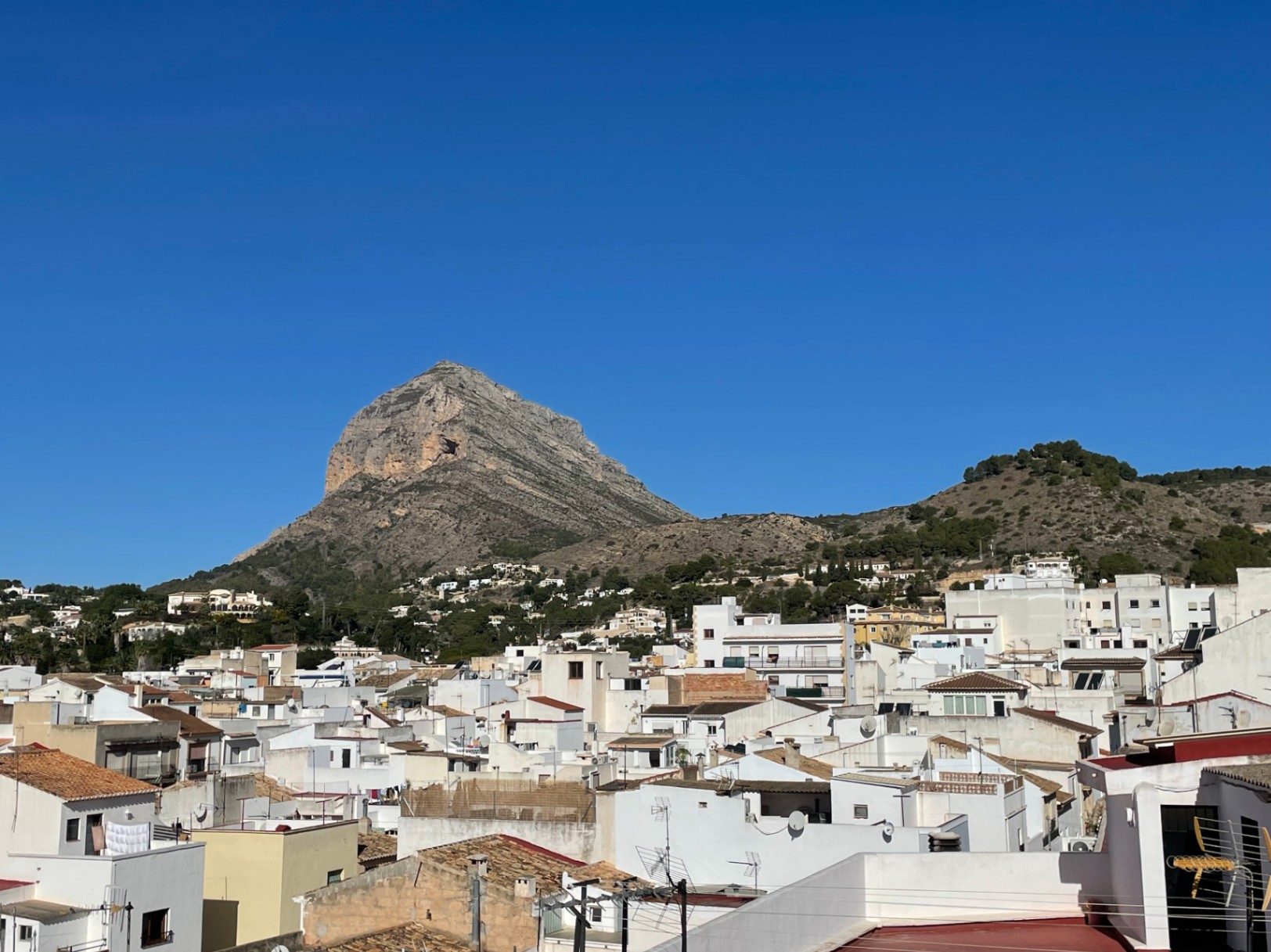 Panoramic rooftop views overlooking the Montgó mountain and Jávea’s historic center, featuring traditional white-washed buildings under a clear blue sky.