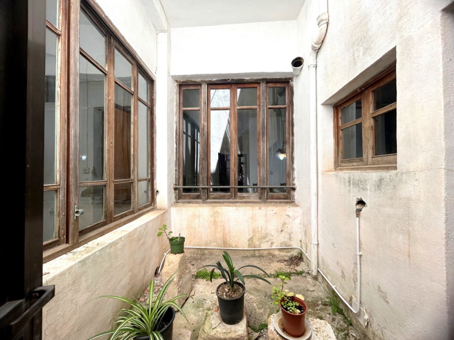 Central light well featuring original large-scale wooden window frames and whitewashed walls, providing natural light and ventilation to the historic interior.