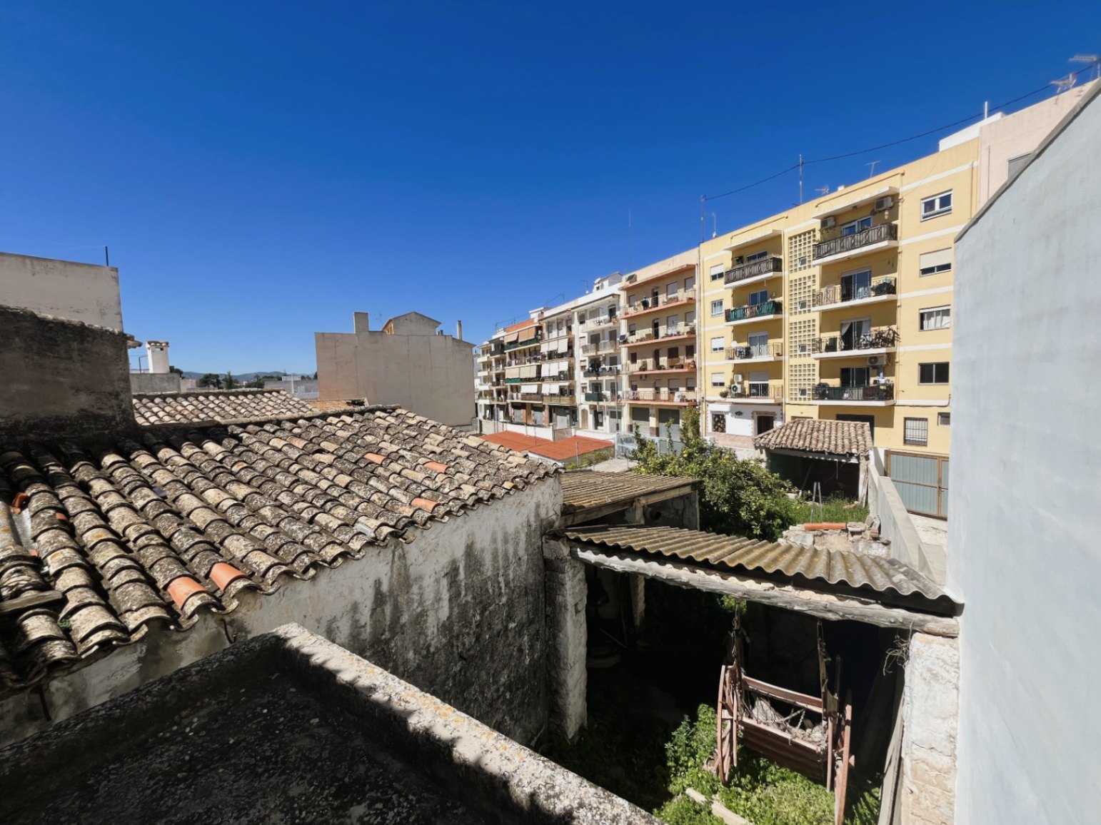 Elevated view of the rear courtyard and traditional clay tile roofs, showcasing the property's integration within the historic urban fabric of Jávea.