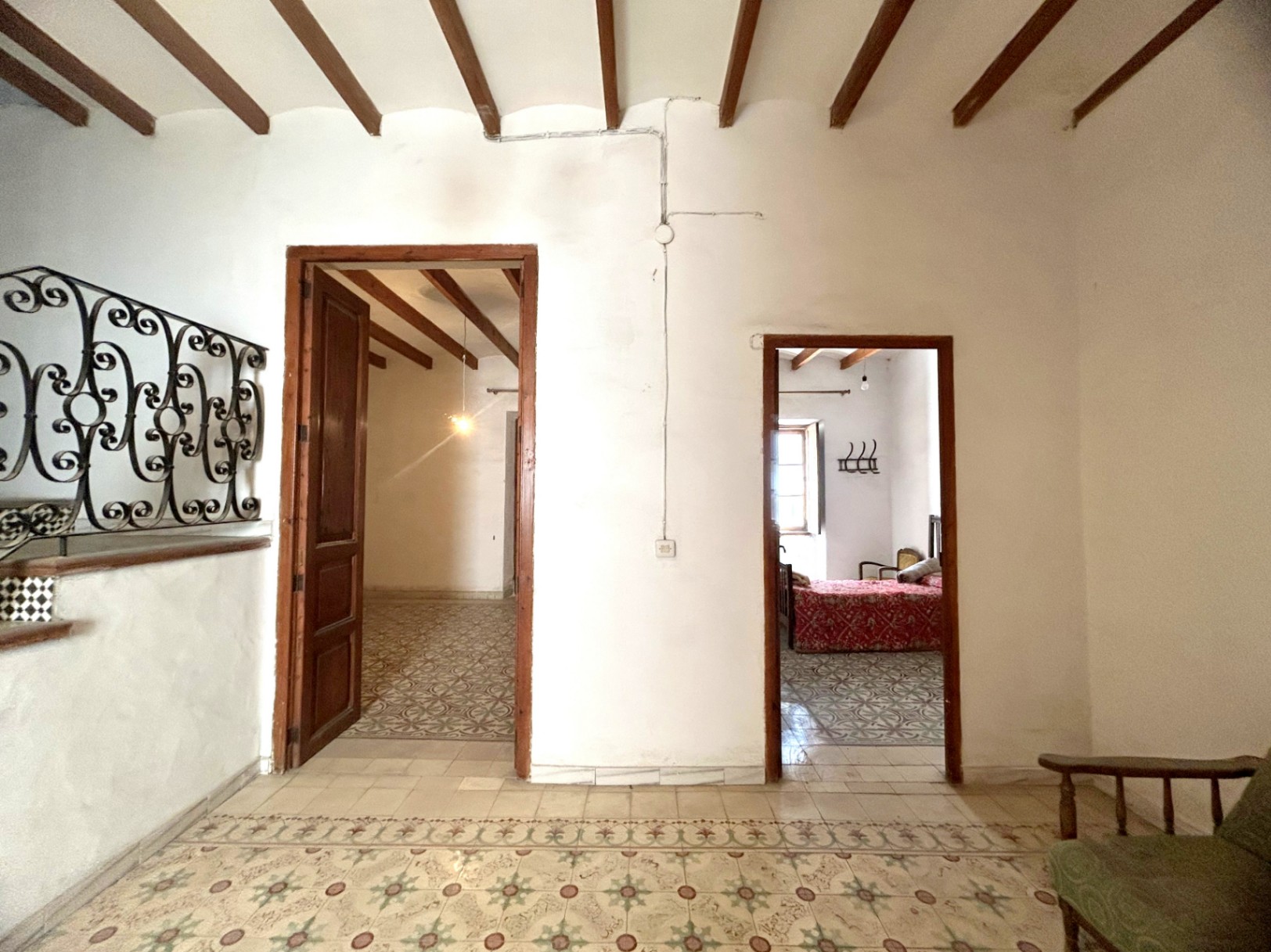 Hallway featuring original hydraulic tile flooring and exposed wooden ceiling beams. It connects to rooms with period woodwork and traditional architectural details.