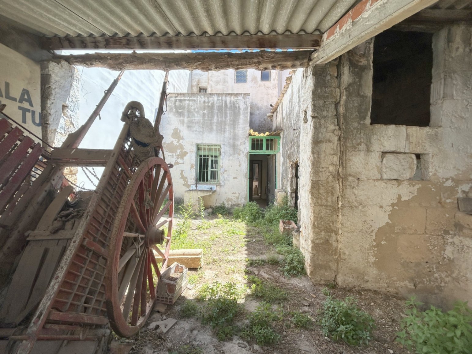 Rear courtyard featuring an antique wooden cart and original stone walls. This outdoor space offers independent access and significant renovation potential.
