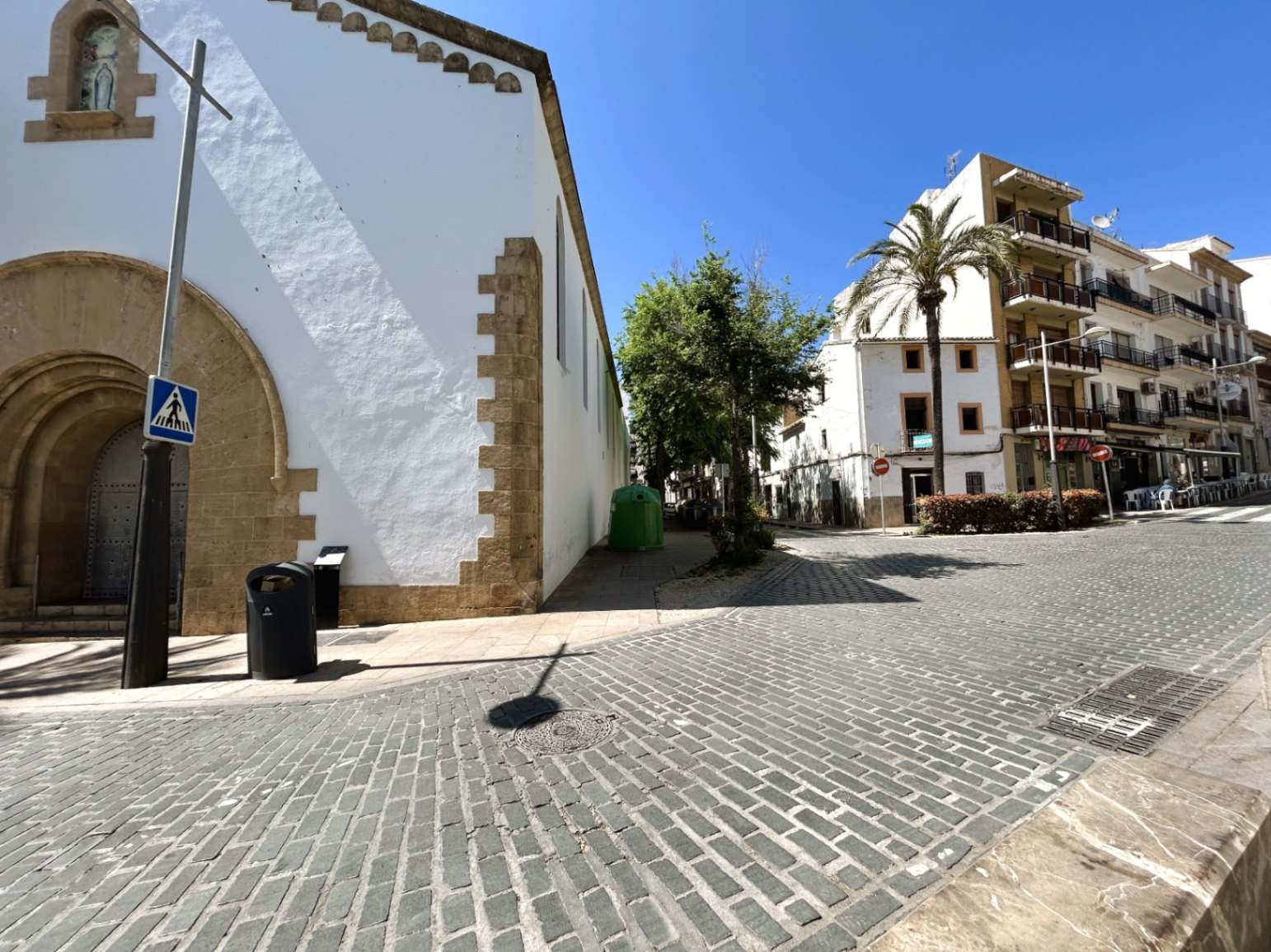 Exterior view of the cobblestone street adjacent to a historic building with traditional Tosca stone arches in Jávea's old town.