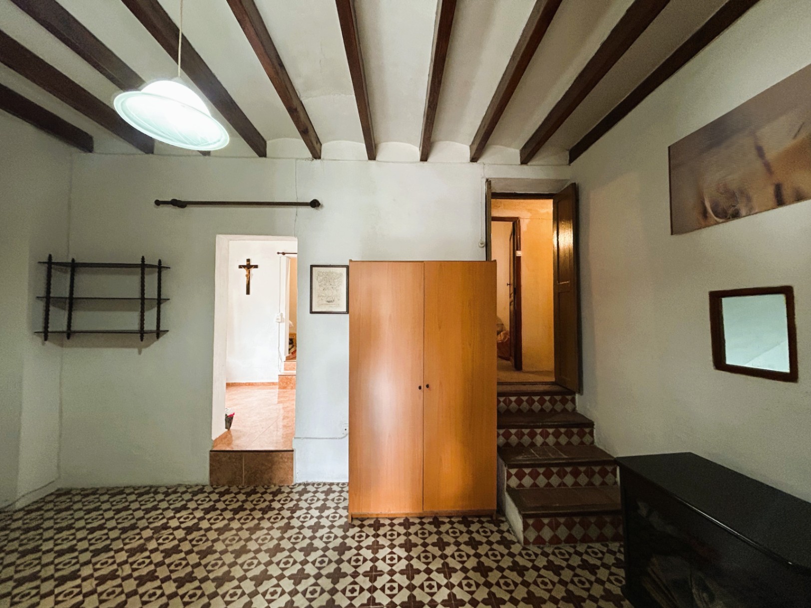 Interior space featuring traditional exposed wooden beams, original patterned hydraulic floor tiles, and a split-level layout with decorative stairs.