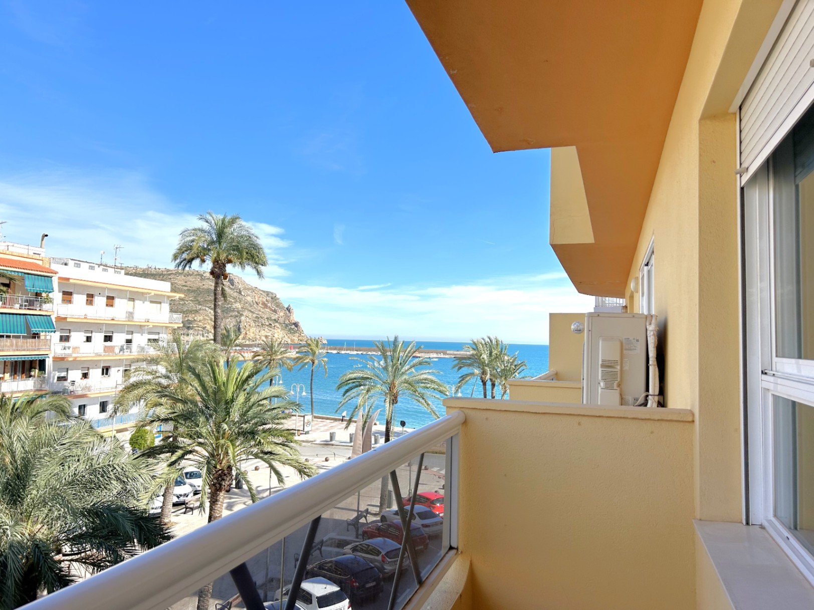 Balcony with direct views of the Mediterranean Sea and Javea Port, featuring palm-lined streets, a metal railing, and white exterior shutters.