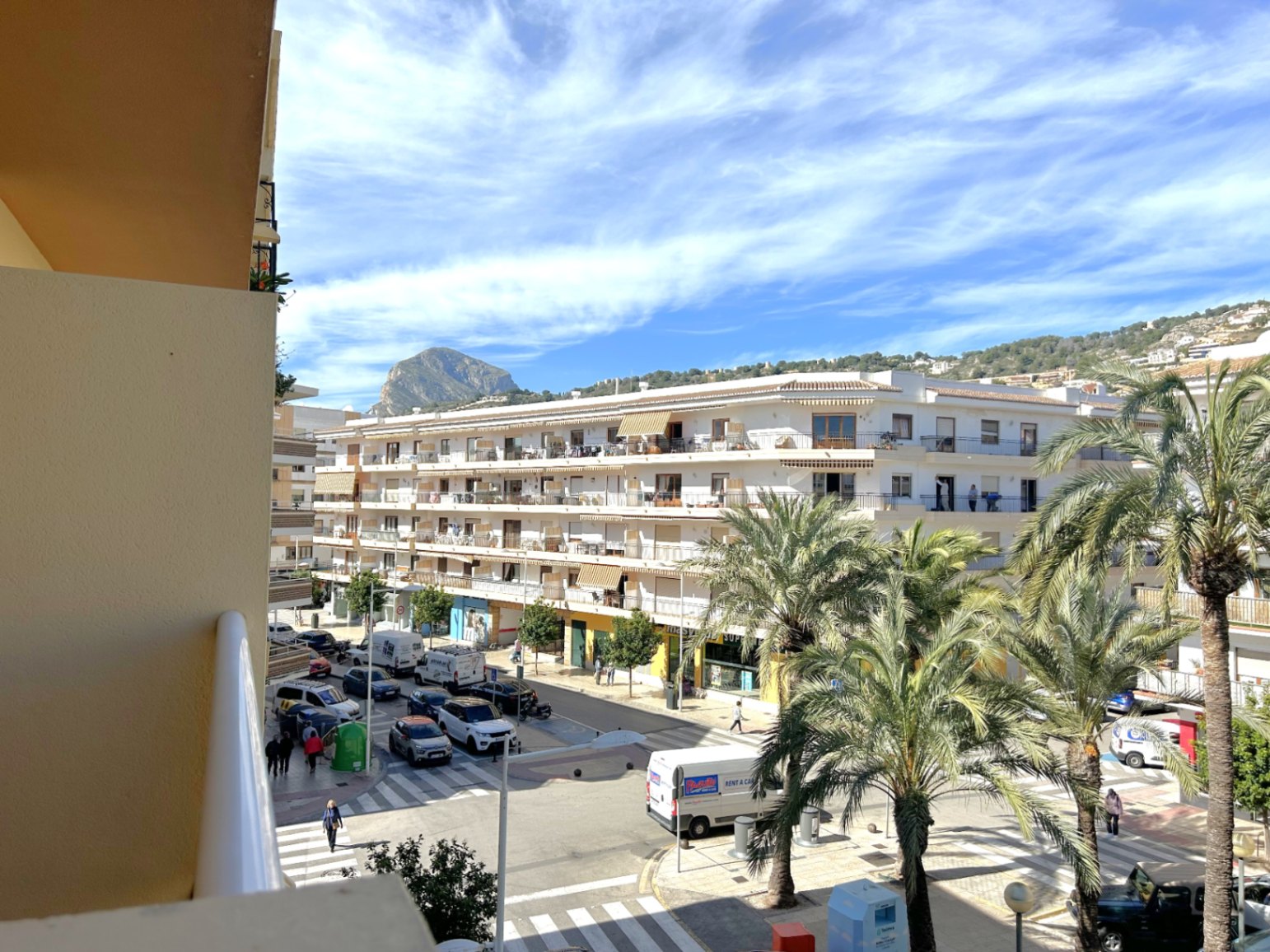Clear views from the balcony over the center of Puerto de Jávea, featuring the iconic Montgó mountain in the distance and streets lined with Mediterranean palm trees.