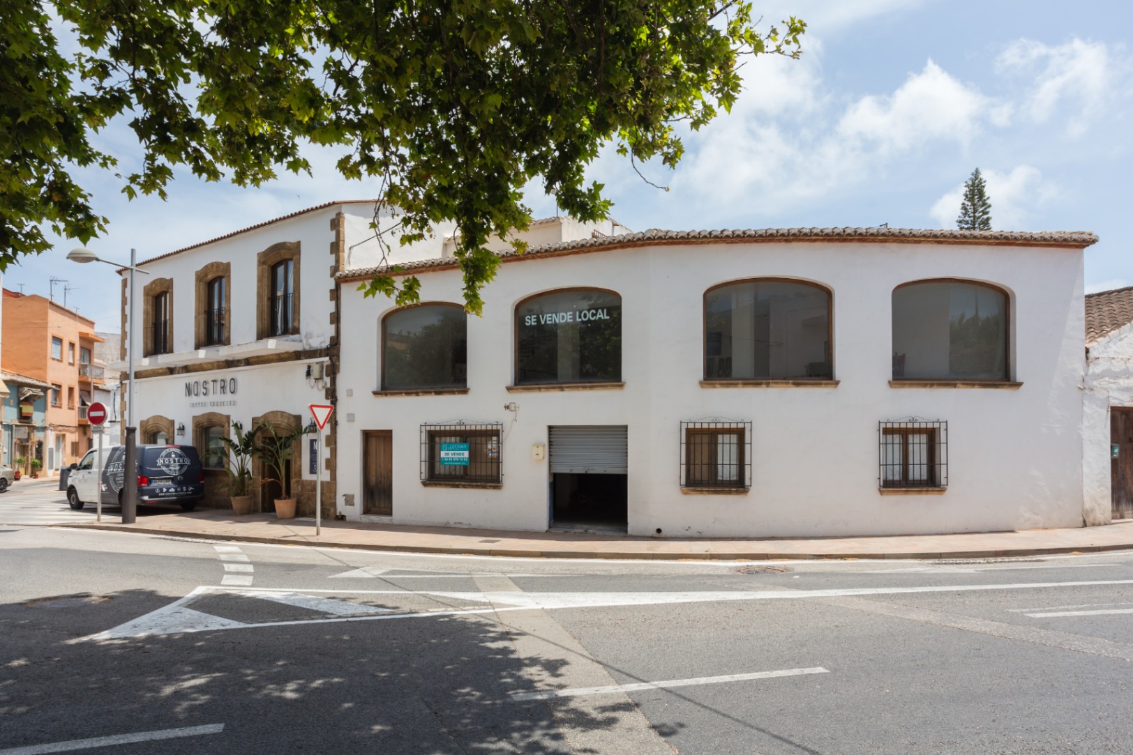 Exterior corner facade in Jávea featuring traditional tosca stone surrounds, large upper-floor windows, and a classic two-story Mediterranean architectural style.