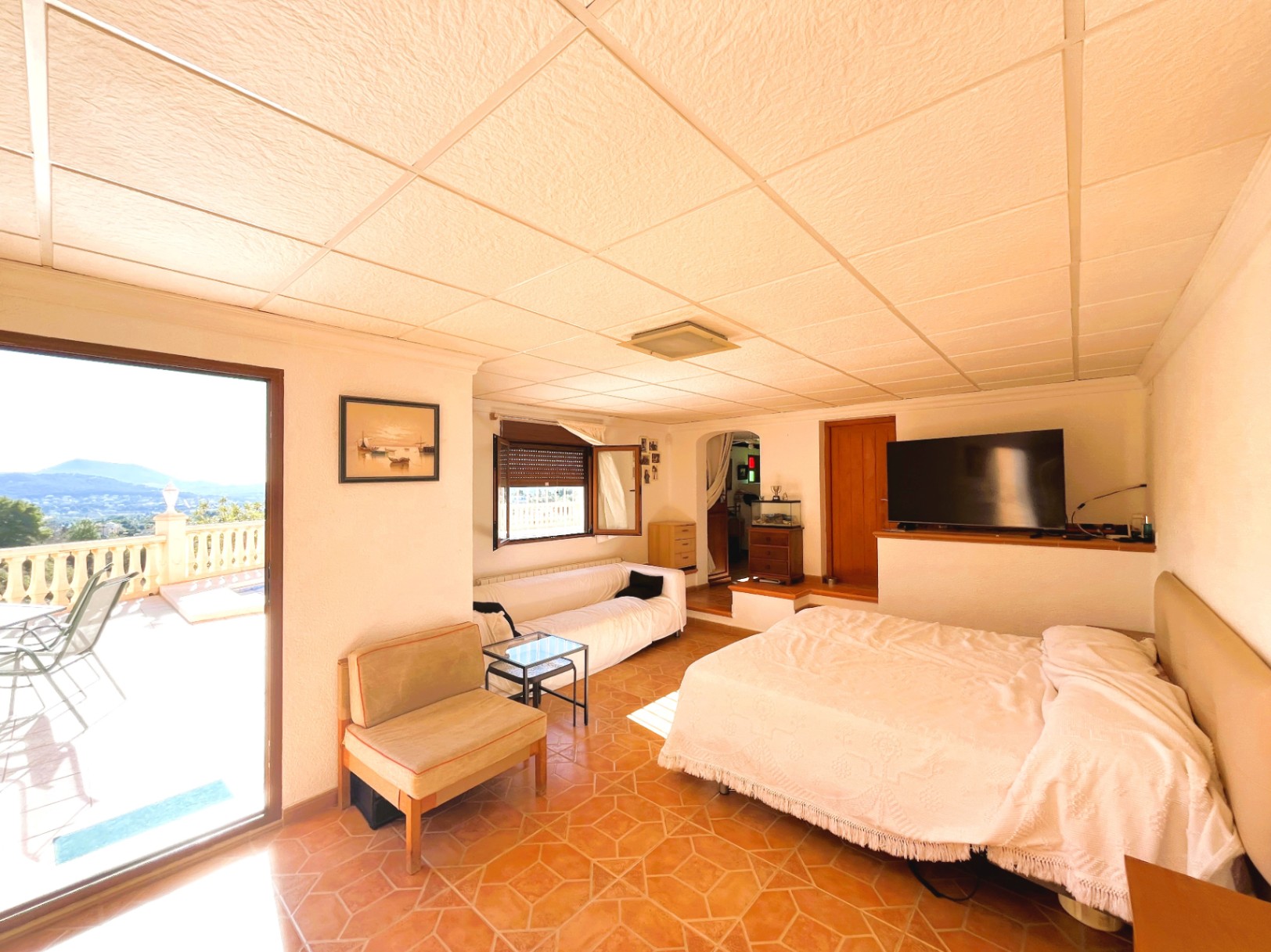 Lower floor guest suite with integrated living area, terracotta-style tiling, and direct access to a terrace with expansive valley views.