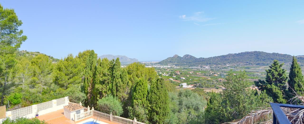 Elevated panoramic views overlooking the lush valley and Mediterranean Sea, featuring the lower pool terrace with its classic stone balustrade.