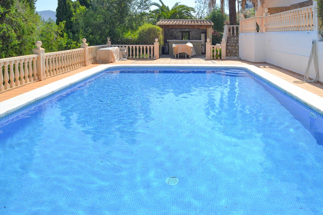 Large 12x6m swimming pool with blue mosaic tiles, featuring a terracotta terrace with stone balustrades and a covered outdoor kitchen bar area.