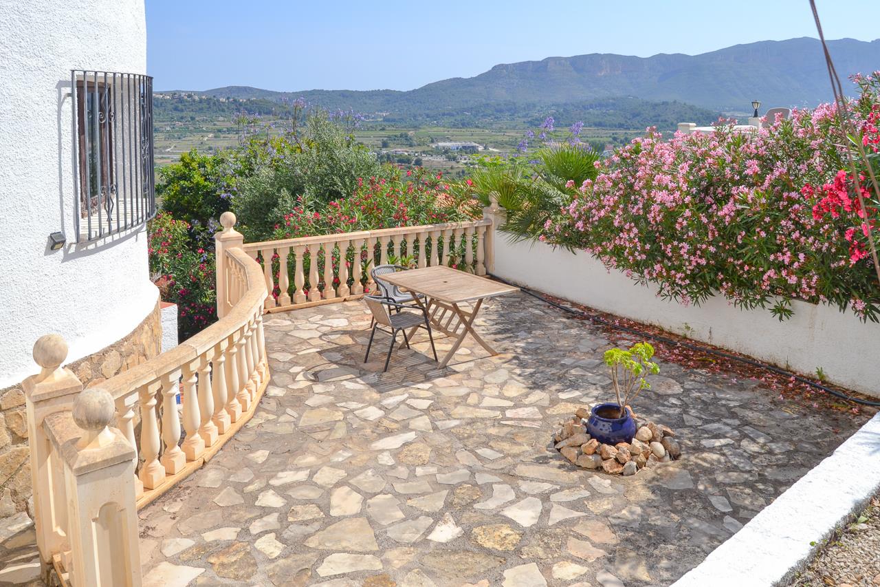 Outdoor terrace featuring irregular stone paving, a classic balustrade, and panoramic views of the valley and surrounding mountains.