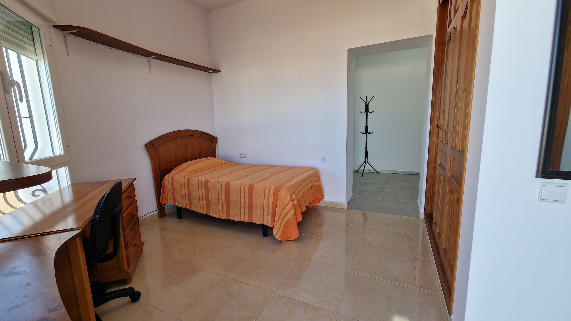 Bedroom with a single bed, wooden desk, and built-in wardrobe.