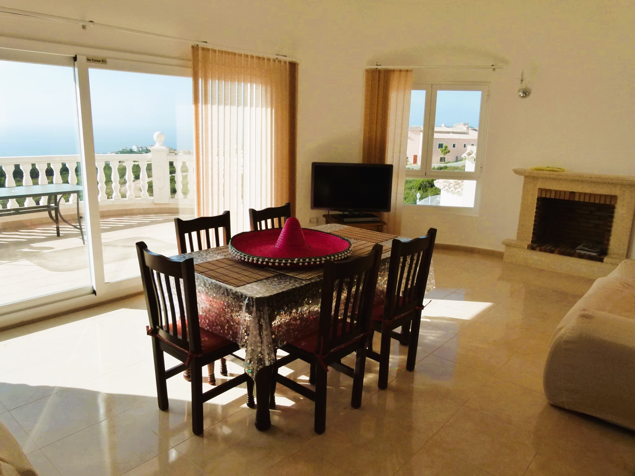 Bright dining room with terrace access and sea views in Benitachell. Table with a red sombrero.