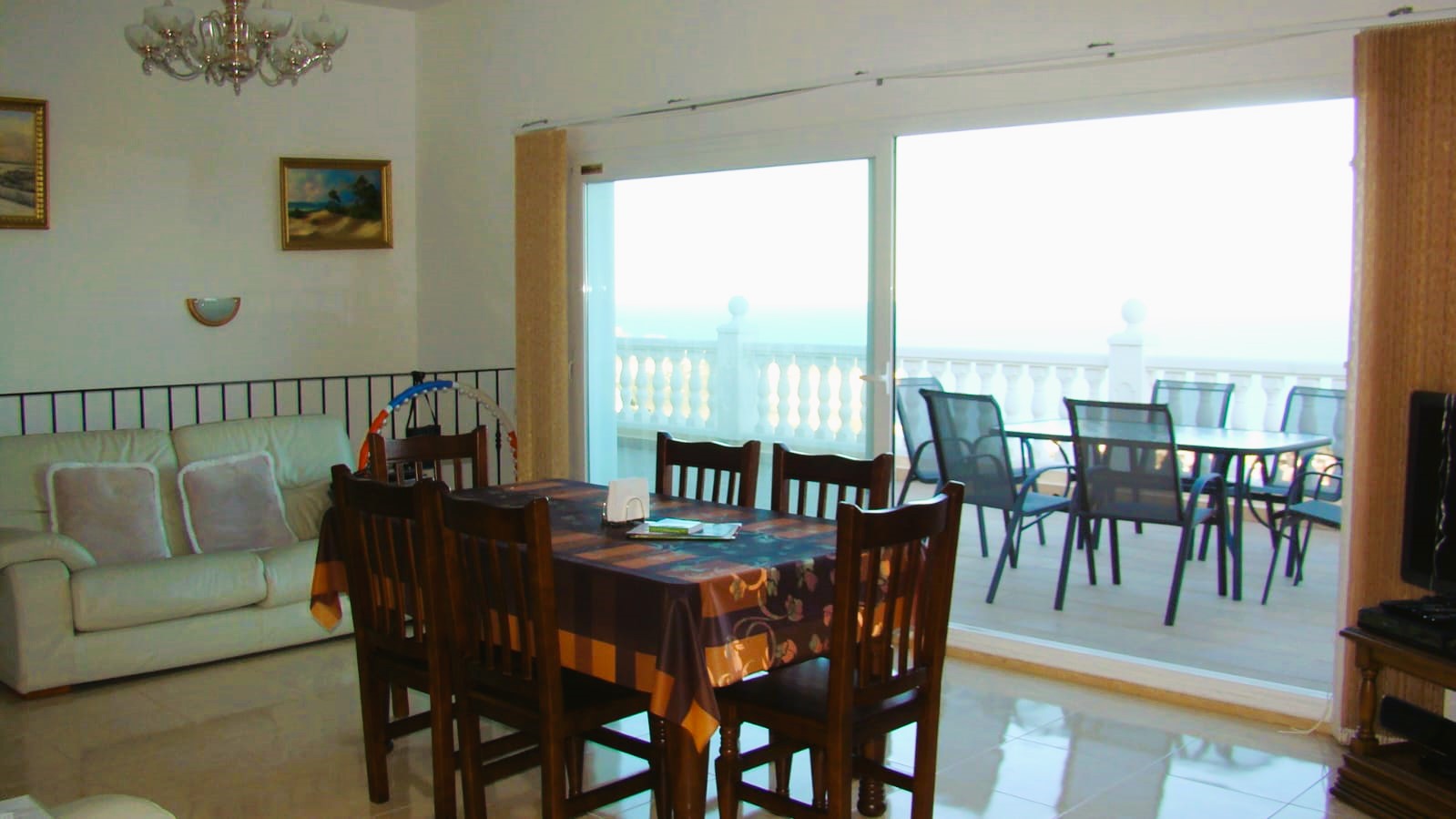 Bright dining room with wood table and access to the terrace with sea views.