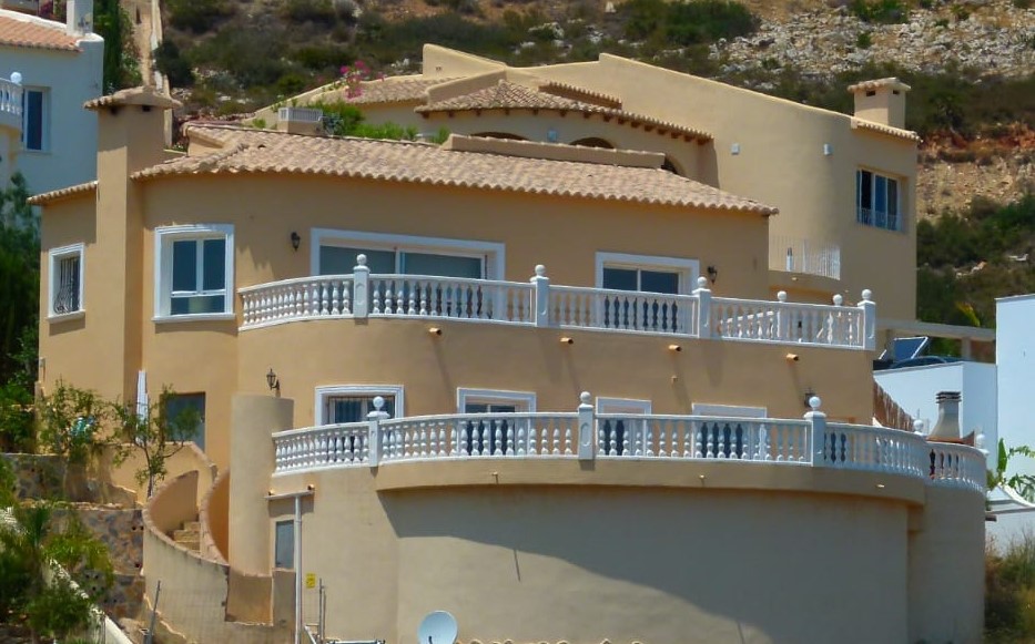 Exterior view of villa featuring curved balconies and white balustrades in Cumbre del Sol.