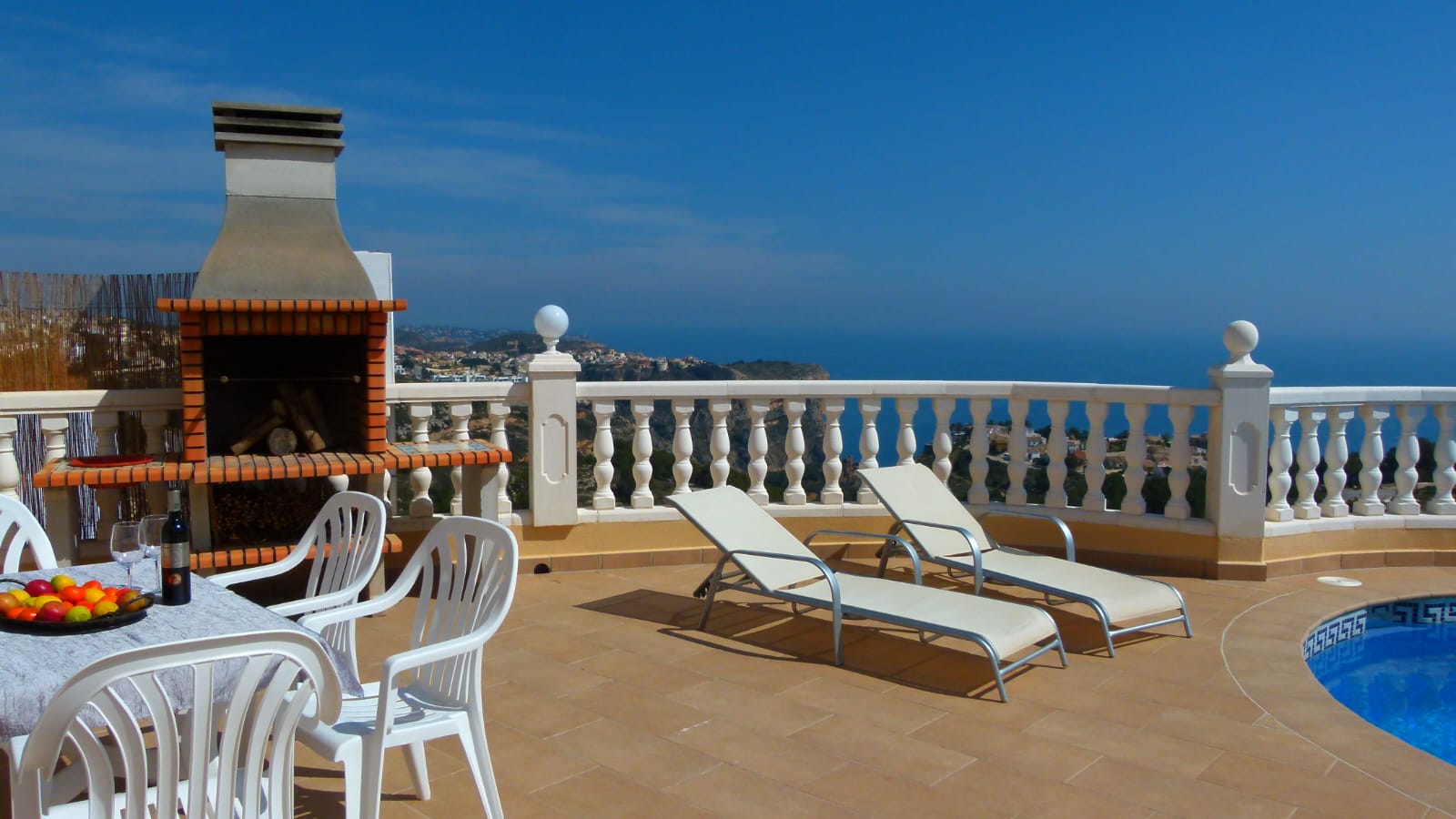 Terrace with brick BBQ, sun loungers, and sea views from Cumbre del Sol, Benitachell.