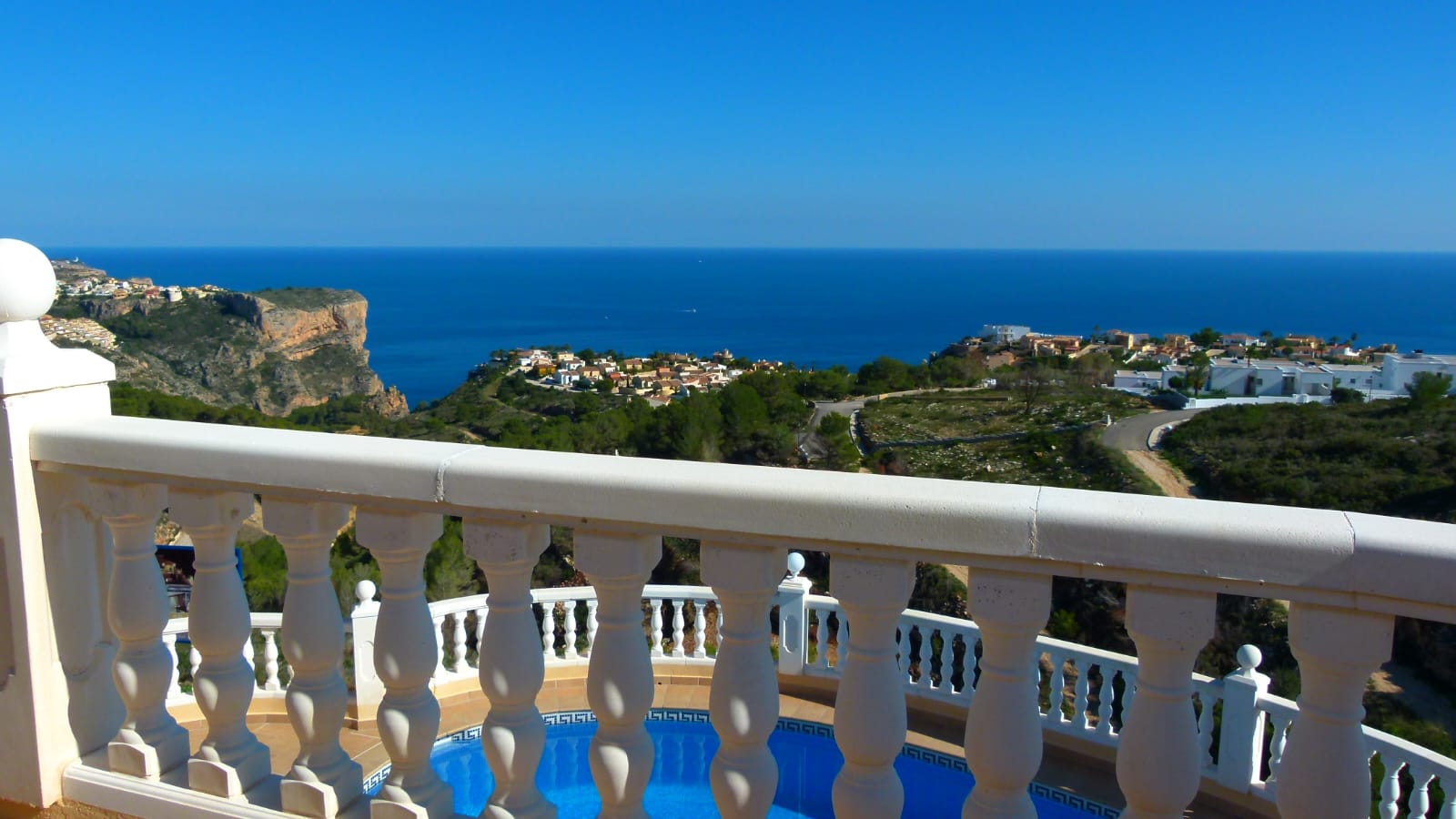 View from the terrace with white balustrade to the pool and the Mediterranean Sea in Cumbre del Sol.