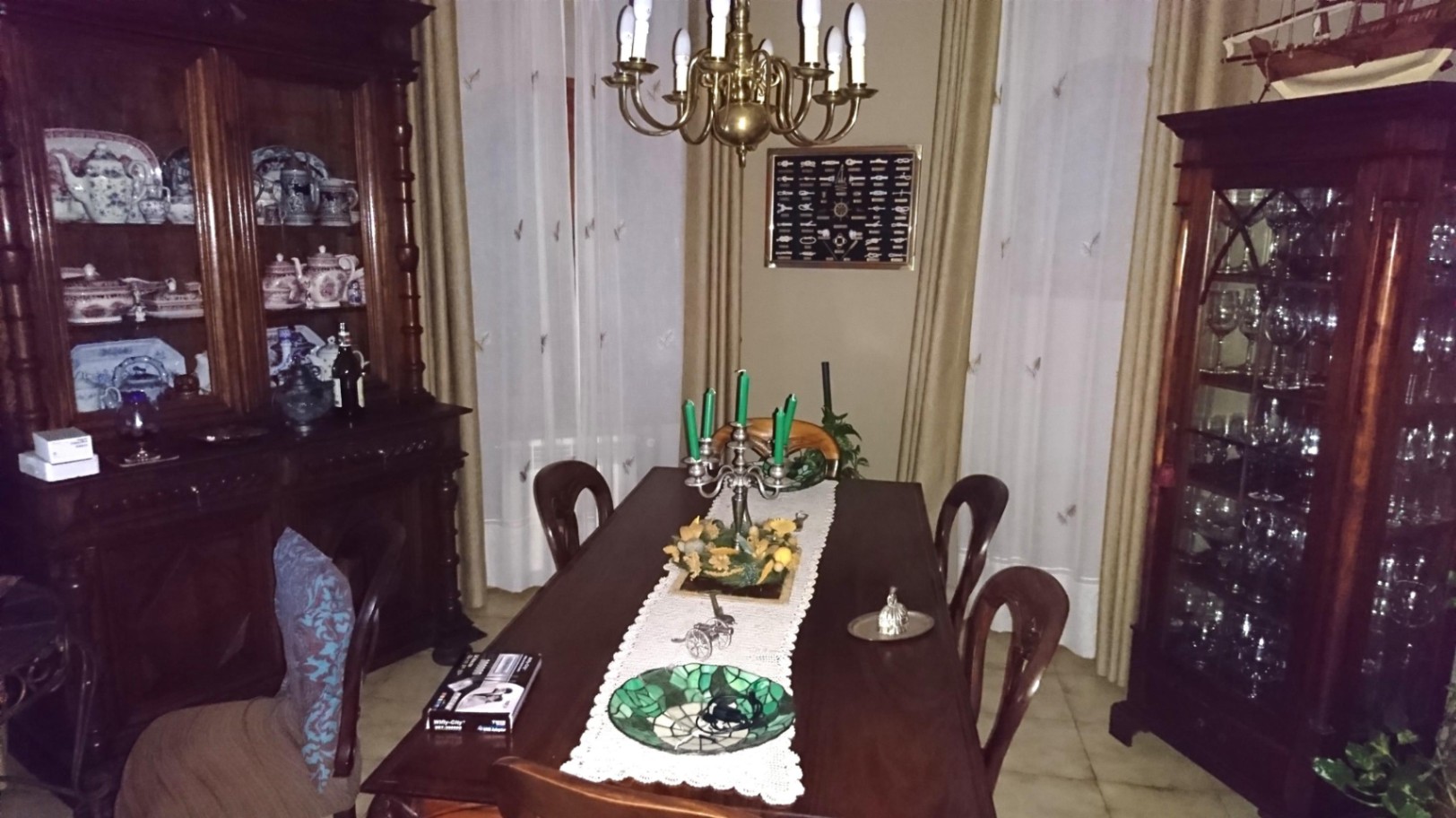 Classic dining room featuring a solid wood table, ornate display cabinets for glassware and china, and a brass chandelier illuminating the traditional decor.