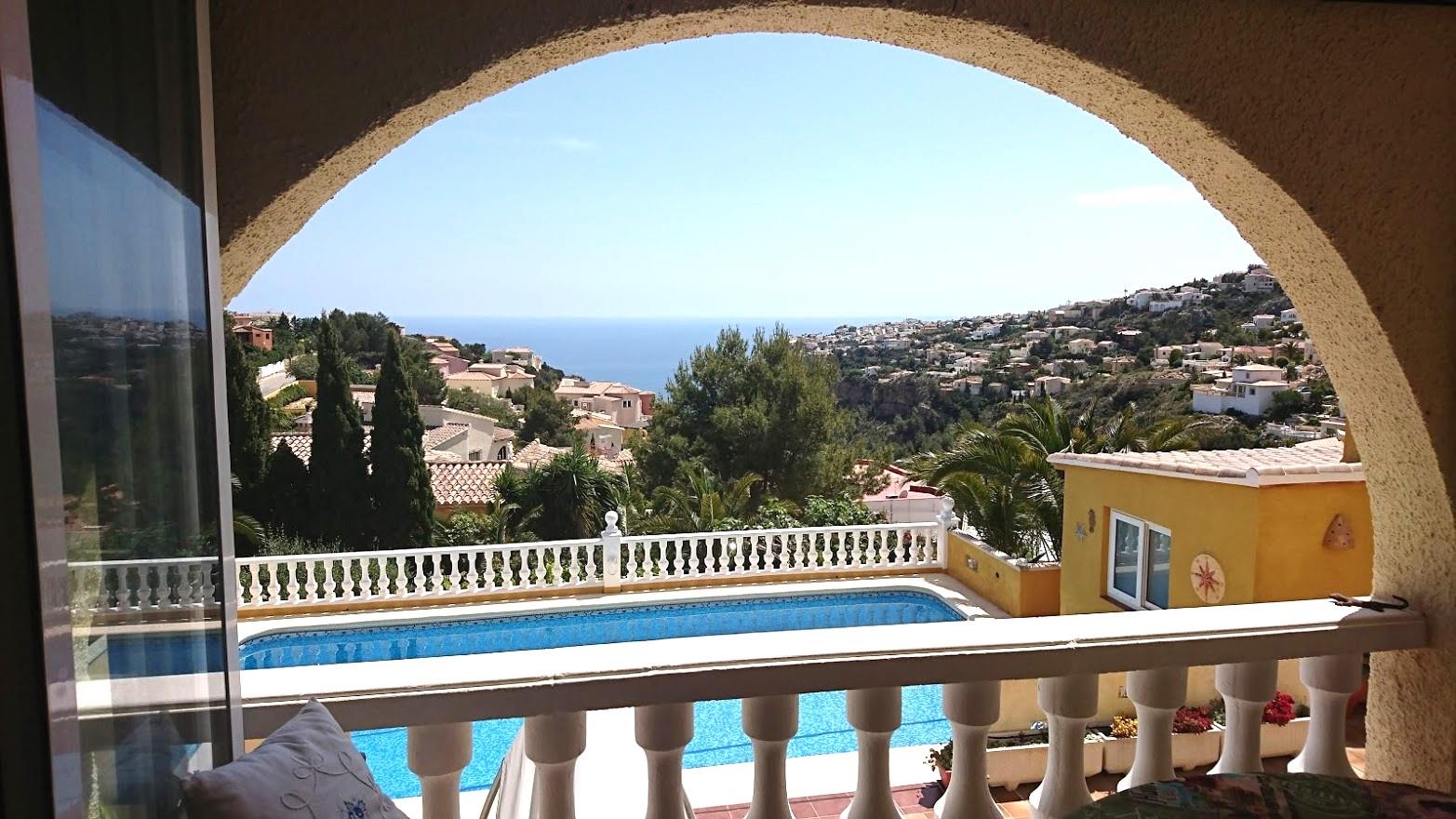 View from the arched terrace overlooking the private swimming pool and the Mediterranean Sea, framed by white balustrades and coastal landscapes.