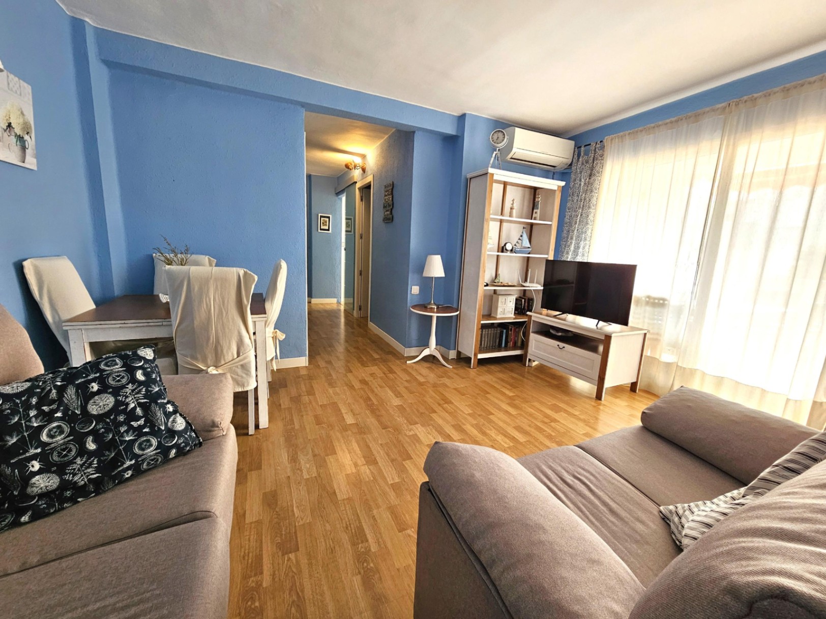 Living and dining area featuring blue walls, parquet flooring, split-system air conditioning, and large windows providing natural light.