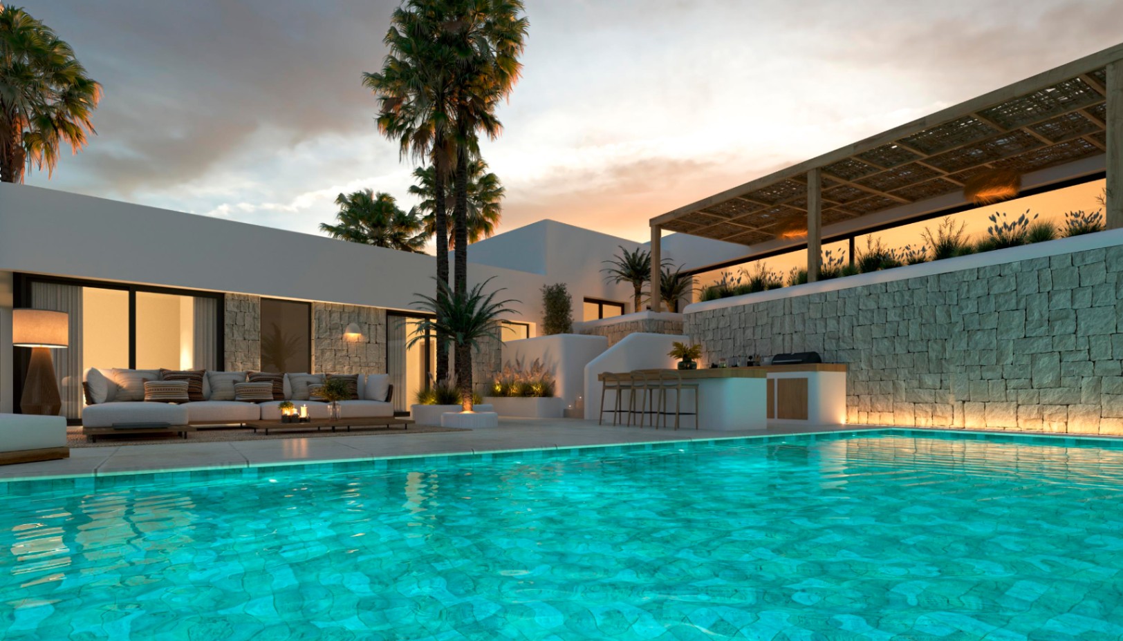 Exterior pool area featuring a turquoise basin, outdoor kitchen with bar, and lounge seating. Natural stone walls, wooden pergolas, and palm trees are highlighted by warm evening lighting.