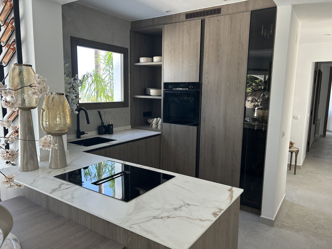 Modern kitchen featuring marble-effect countertops, integrated induction hob, and dark wood cabinetry. Includes a matte black sink and built-in appliances.