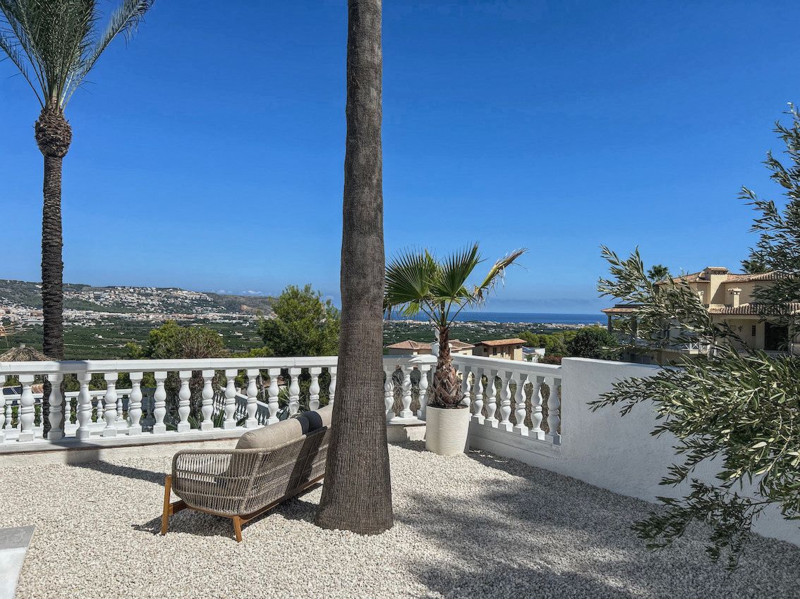 Outdoor terrace featuring white gravel, modern seating, and a classic balustrade overlooking the valley and the Mediterranean Sea.