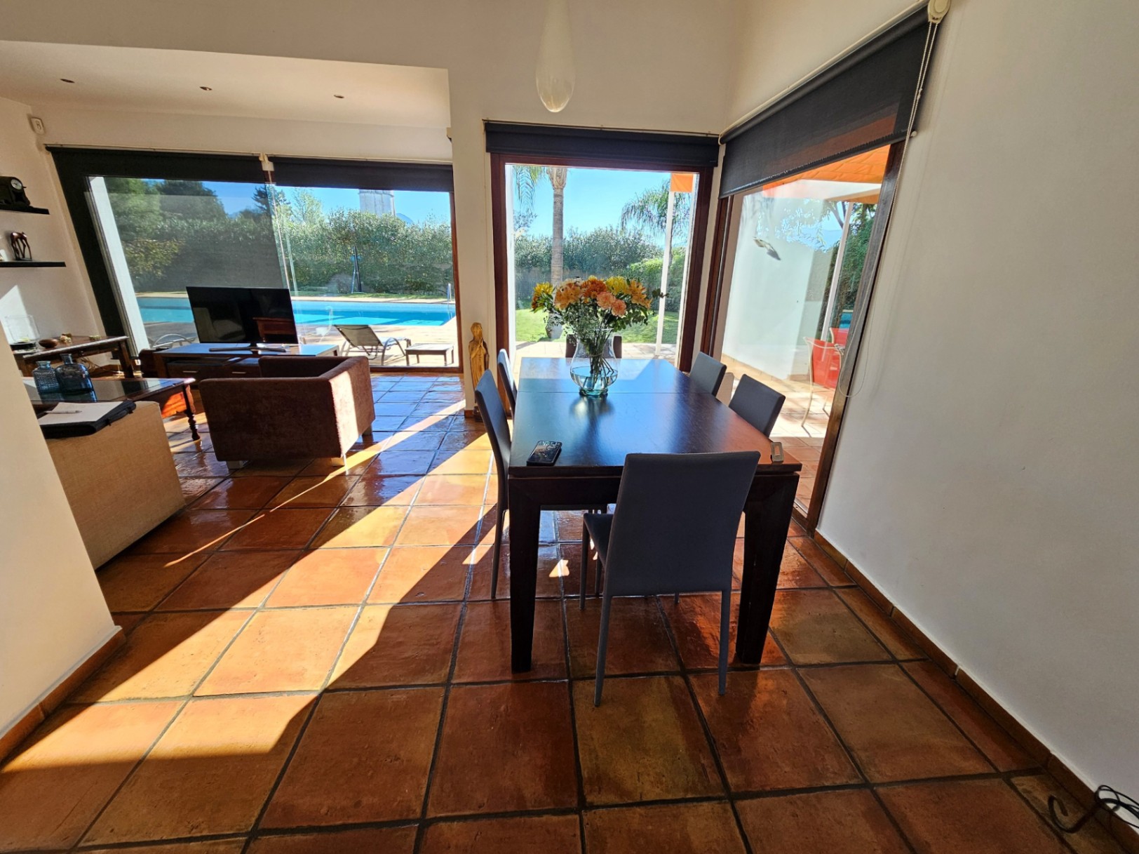 Dining area featuring handmade clay tile flooring and large security glass windows with direct views of the swimming pool and garden.