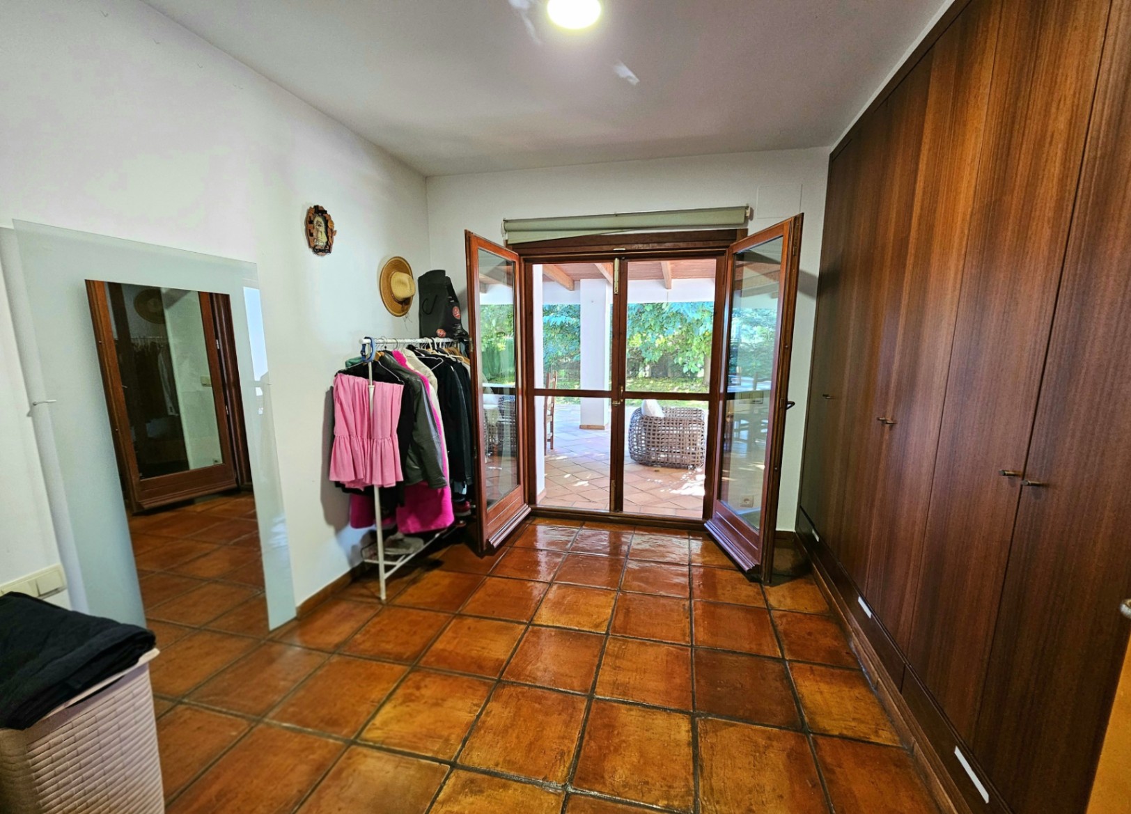 Dressing room featuring large built-in wooden wardrobes, handmade terracotta flooring, and direct access to the outdoor terrace through glass doors.